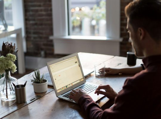 man operating laptop on top of table