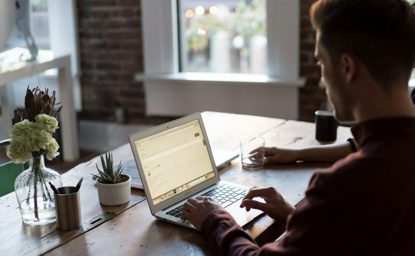 man operating laptop on top of table