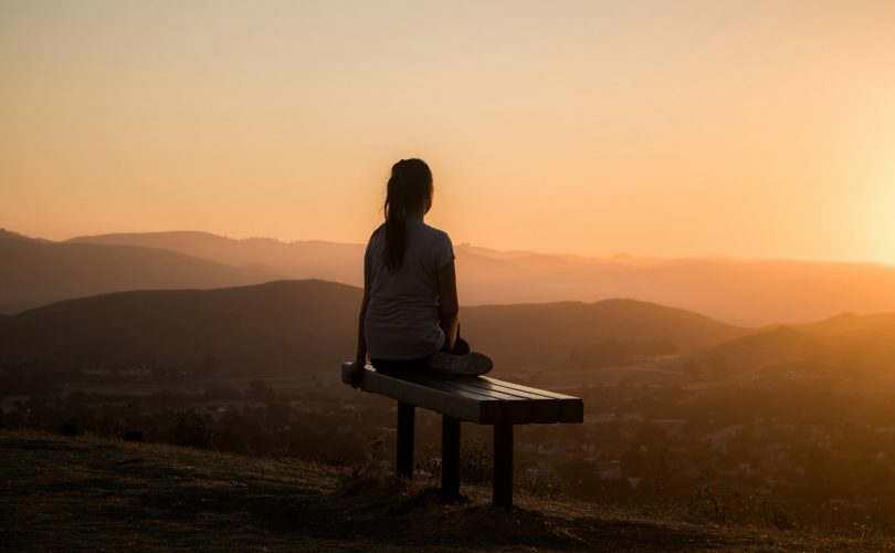 woman sitting on bench over viewing mountain